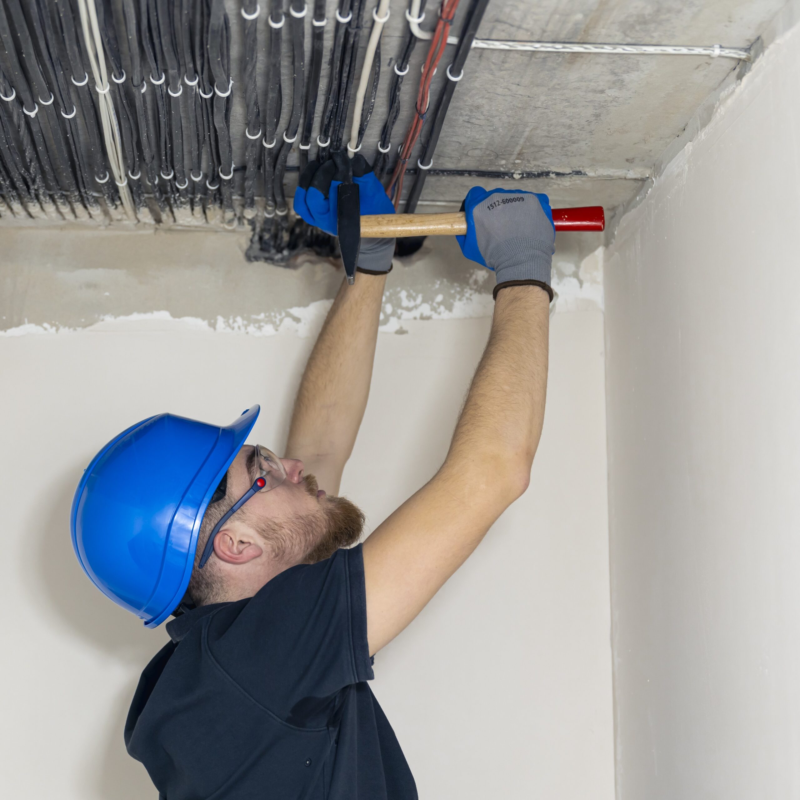 Electrician installing laying electrical cables on the ceiling inside the house.